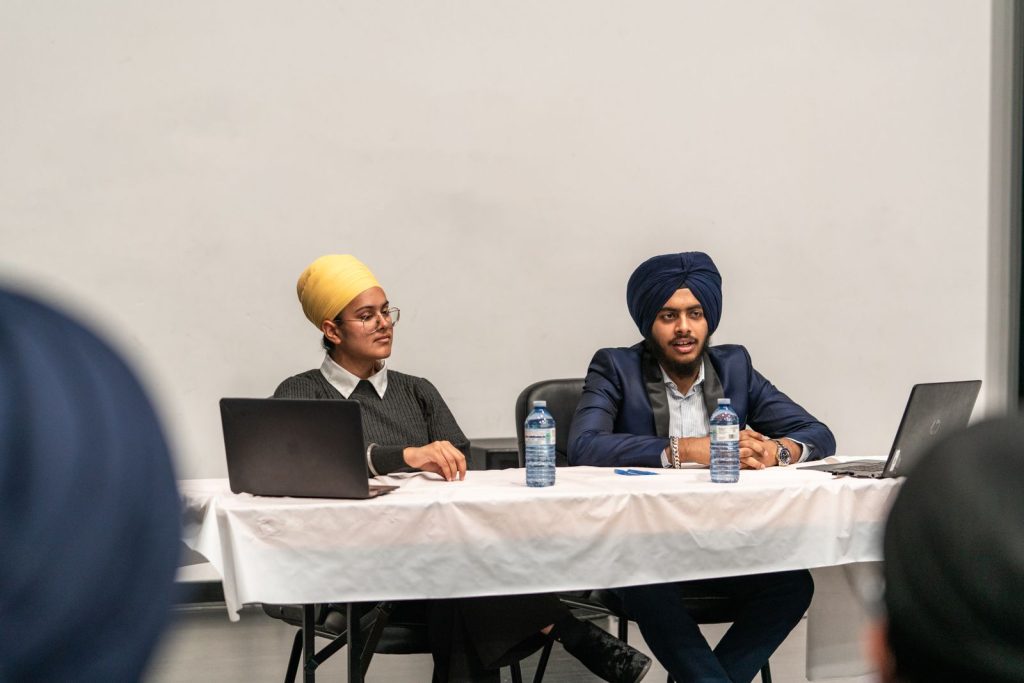 Two Sikh professionals presenting at a conference table