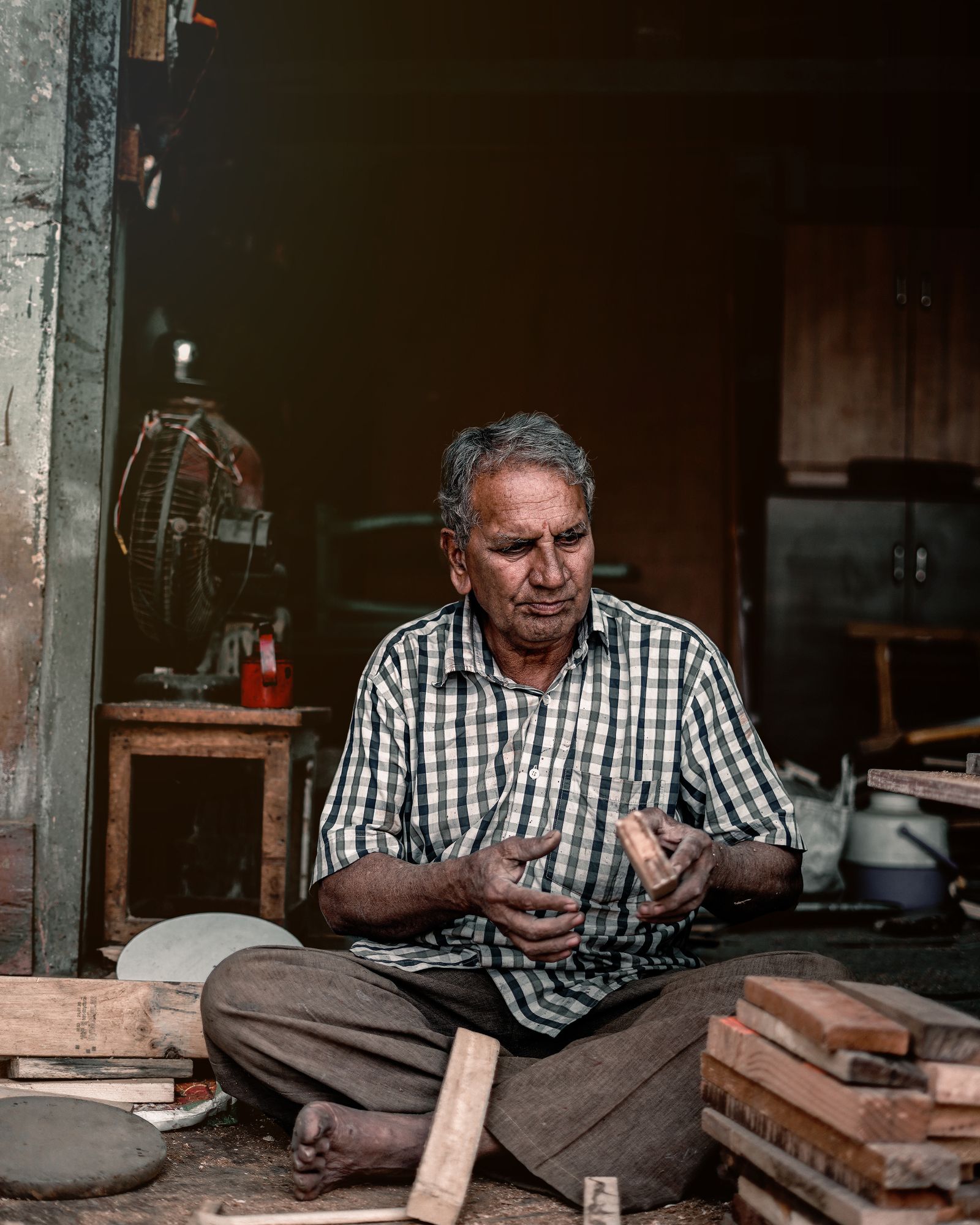 A craftsman working with wood in a workshop in Kalol, India