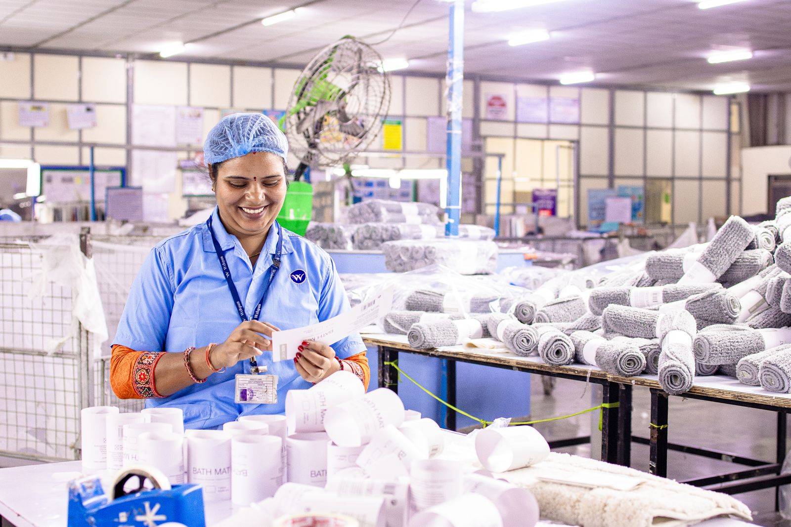 A woman arranging finished towels on the floor of a textile mill in India