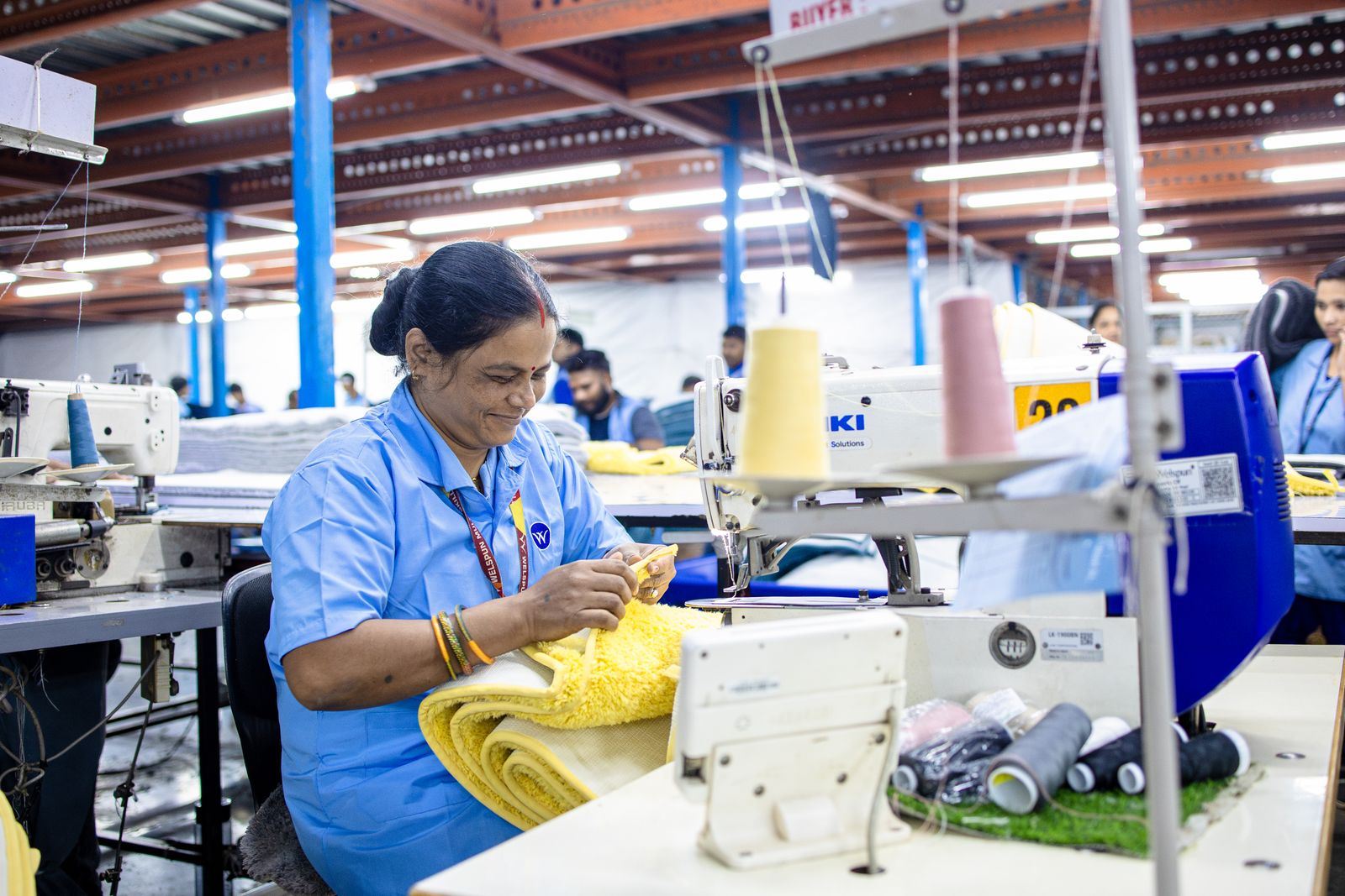 An Indian woman sewing fabric in a textile unit