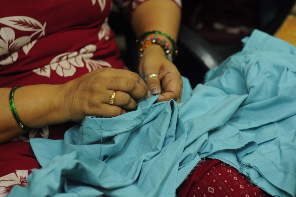 A woman hand-sewing blue fabric in Kolkata, India